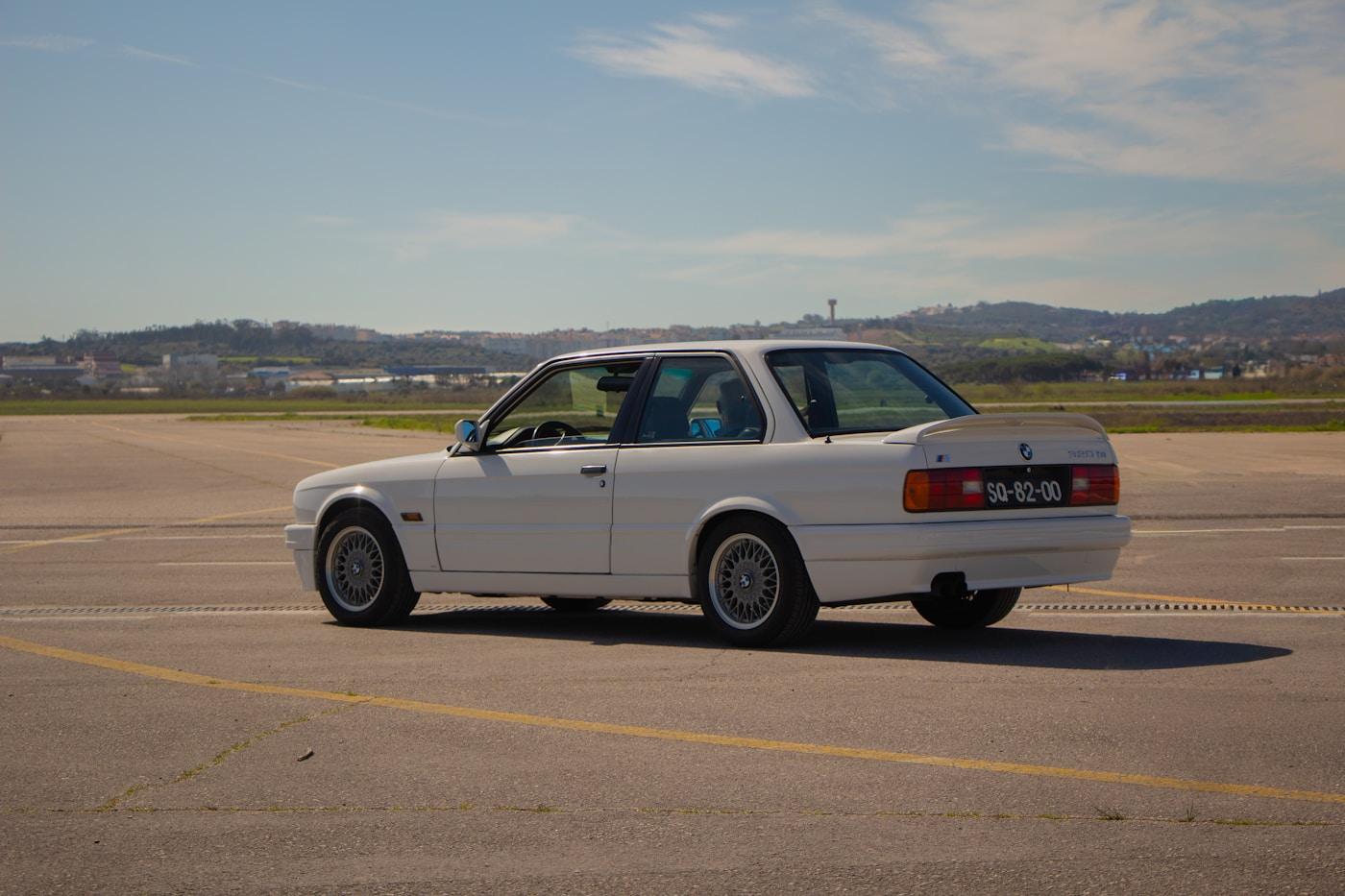 A driver-quality BMW E30 photographed in open daylight